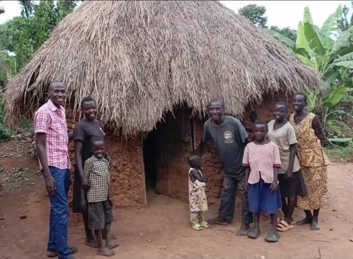Julius and his children standing outside the hut