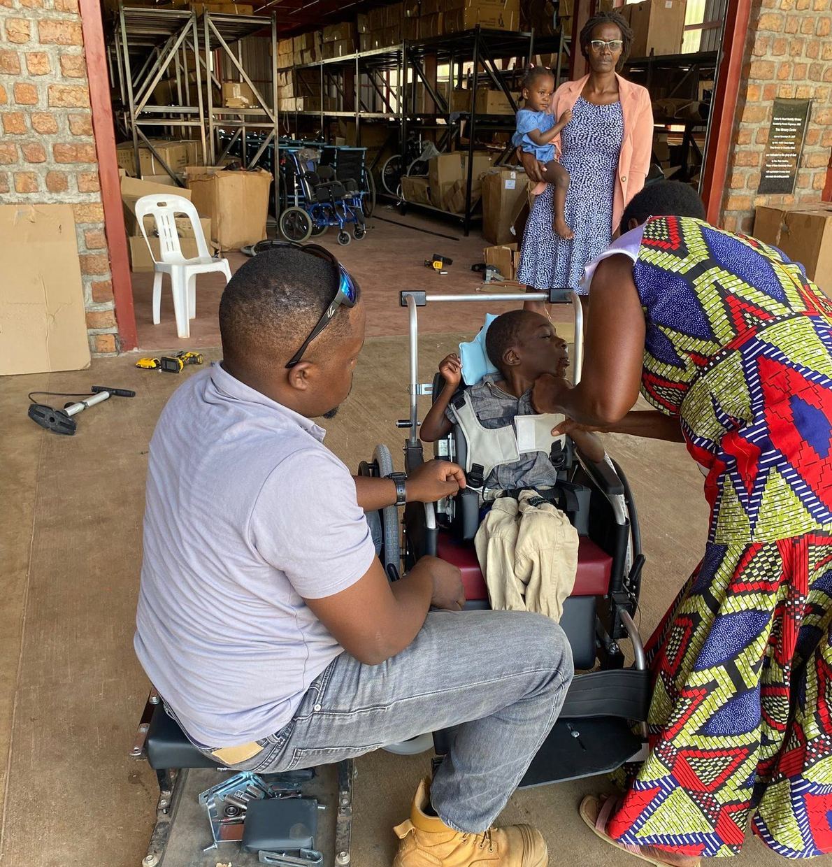 Inside the Father’s Heart workshop, a technician setting up Solomon’s chair while his caregiver steadies his head