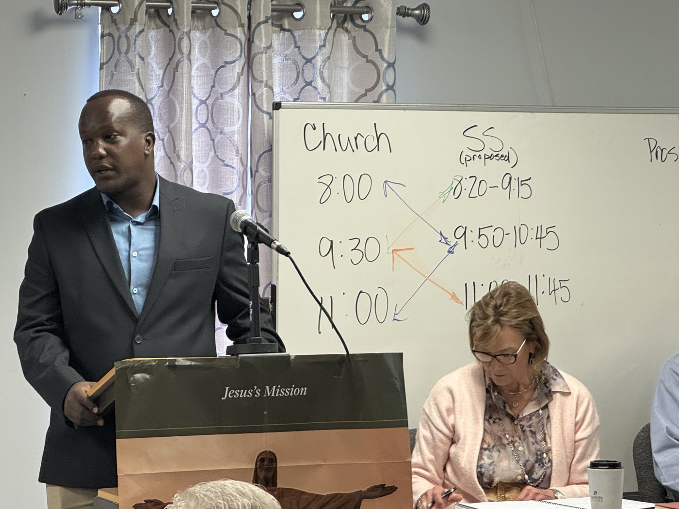 Enock Nkulanga speaking at a podium to the Empty Nesters class