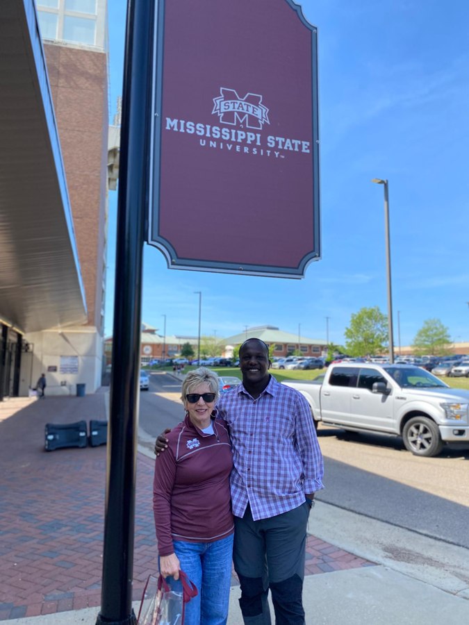 Enock Nkulanga with Vicki Alston under a Mississippi State University banner
