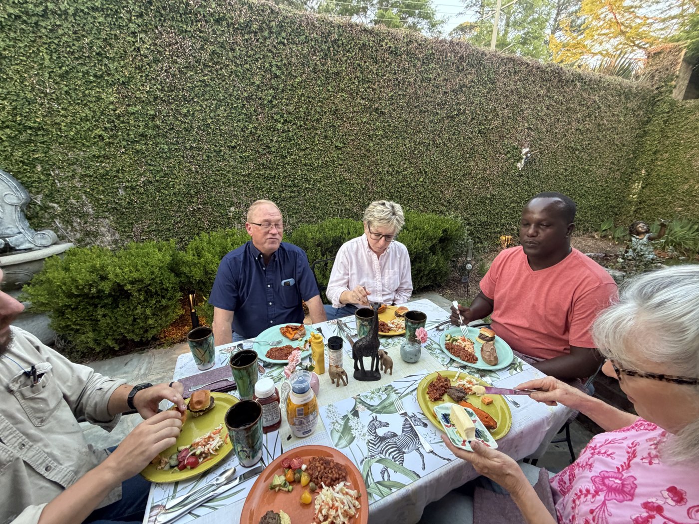 Enock sharing supper with friends at a garden table